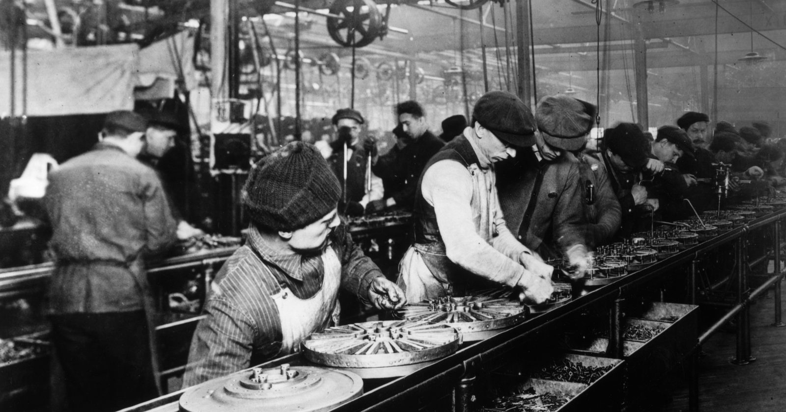 Robotnicy przy pierwszej ruchomej linii montażowej Forda w Highland Park składają podzespoły do aut z 1913 roku.